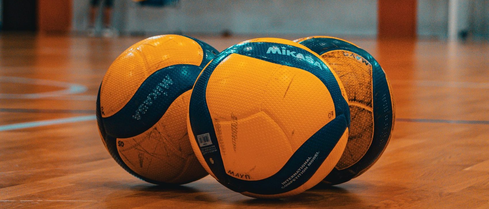 Drei Volleybälle auf einem Hallenboden